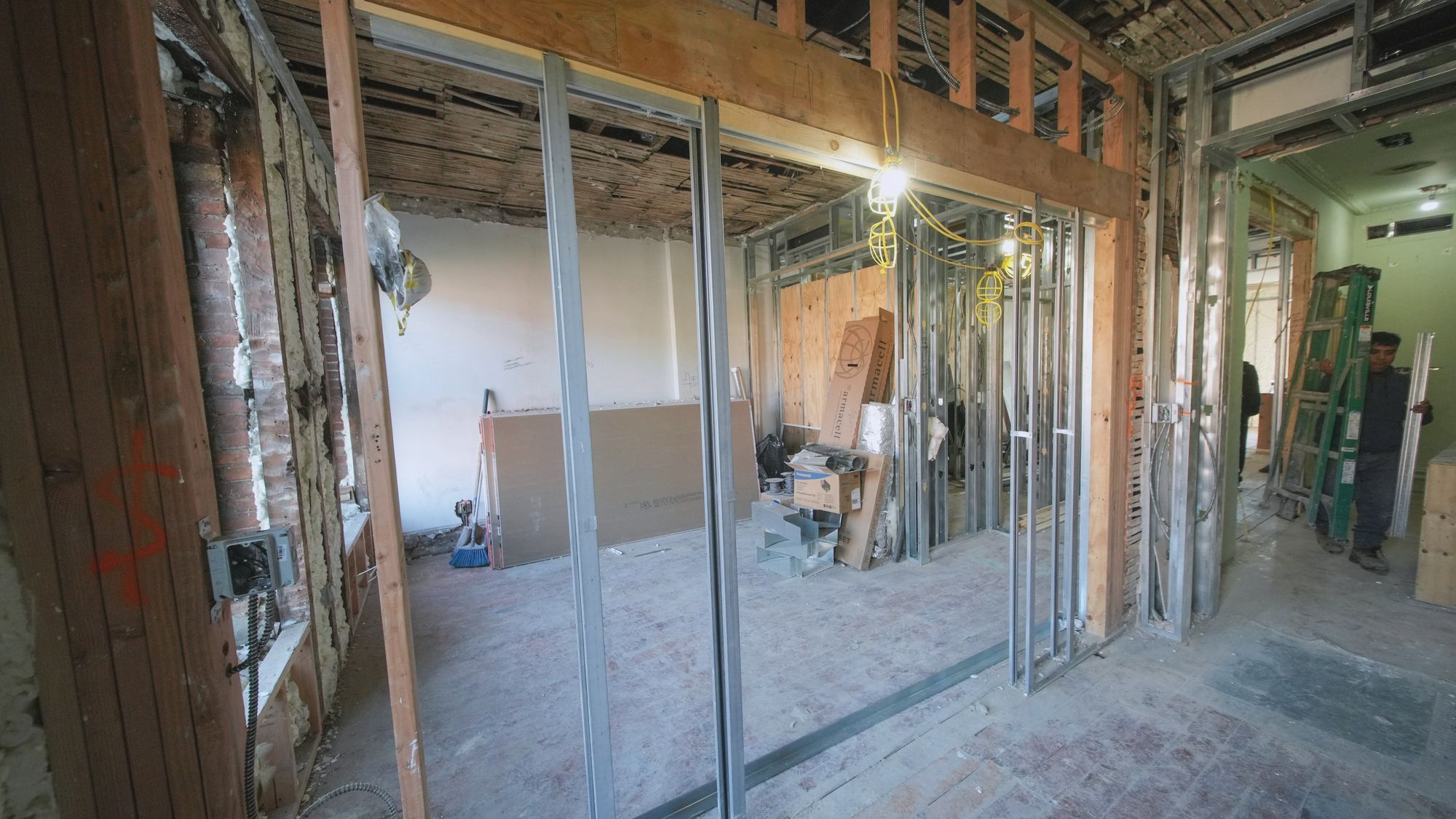 An interior fit-out with open steel stud walls, exposed cables and temporary lighting before the boards go up