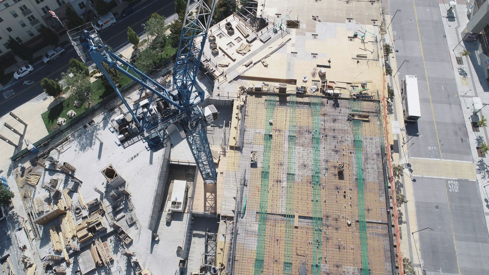 Aerial view of a city construction site with a tower crane and a rebar deck