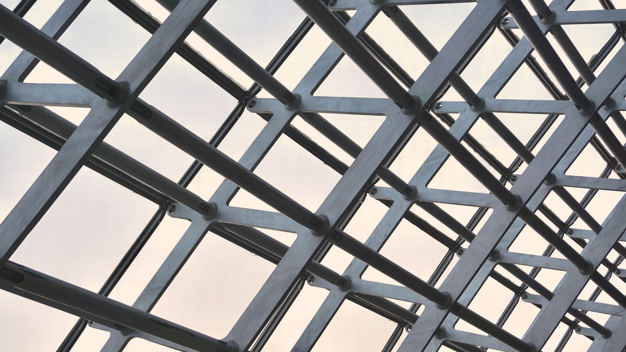 A steel space-frame roof seen from below, its members crossing in a dense lattice